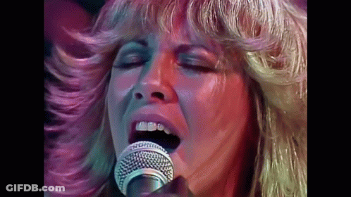 A Close Up Of A Woman Singing Into A Microphone GIF