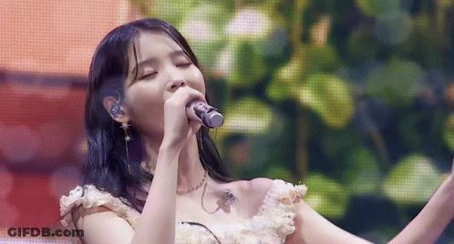 A Close Up Of A Woman Singing Into A Microphone On A Stage . GIF
