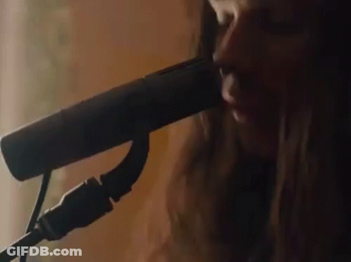 A Close Up Of A Woman Singing Into A Microphone GIF