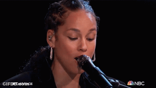 A Close Up Of A Woman Singing Into A Microphone With The Nbc Logo In The Corner GIF