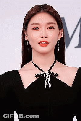 A Close Up Of A Woman Wearing A Black Dress With A Bow Around Her Neck . GIF