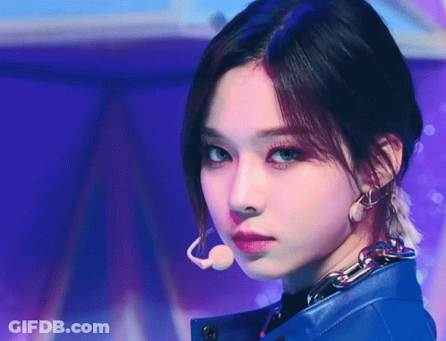 A Close Up Of A Woman Wearing A Blue Jacket And Earrings GIF