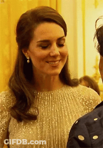 A Close Up Of A Woman Wearing A Dress And Earrings Smiling . GIF