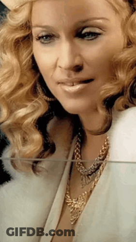 A Close Up Of A Woman Wearing A Fur Coat And Gold Necklace GIF