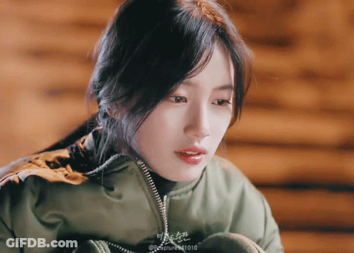 A Close Up Of A Woman Wearing A Green Jacket With The Number 1010 On The Bottom Right GIF