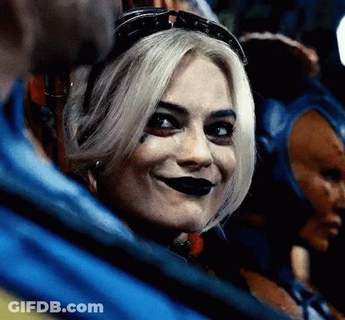 A Close Up Of A Woman Wearing A Harley Quinn Costume And Sunglasses Smiling . GIF