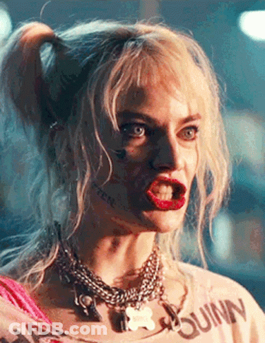 A Close Up Of A Woman Wearing A Harley Quinn Shirt And Necklace . GIF