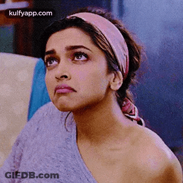 A Close Up Of A Woman Wearing A Headband And A Sweater Looking Up . GIF