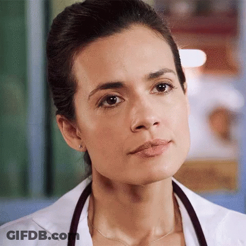 A Close Up Of A Woman Wearing A Lab Coat And Stethoscope Around Her Neck GIF