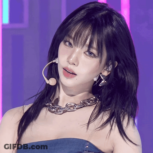 A Close Up Of A Woman Wearing A Microphone And A Chain Around Her Neck GIF