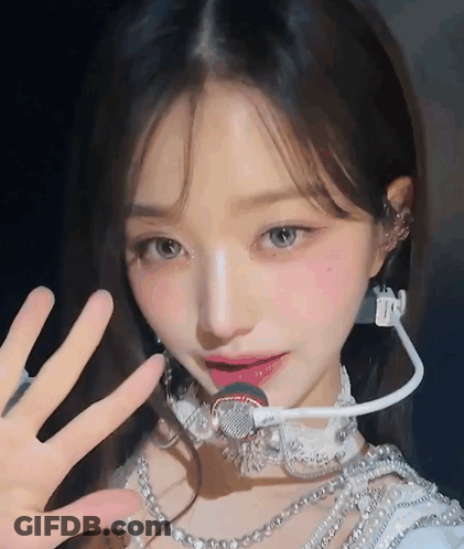 A Close Up Of A Woman Wearing A Microphone And Pearls GIF