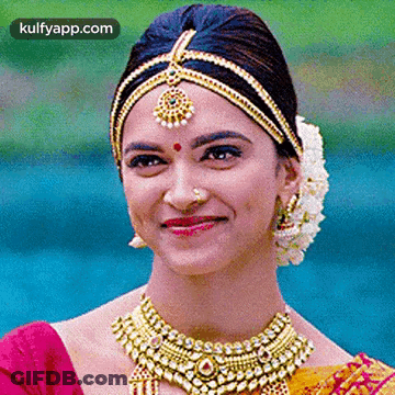 A Close Up Of A Woman Wearing A Necklace And A Headpiece Smiling . GIF