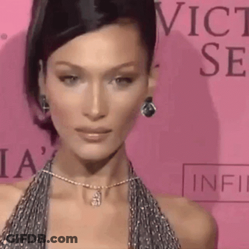A Close Up Of A Woman Wearing A Necklace And Earrings On A Pink Carpet . GIF