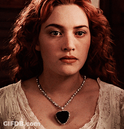 A Close Up Of A Woman Wearing A Necklace With A Heart Shaped Pendant GIF