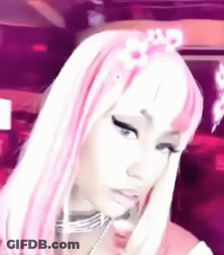 A Close Up Of A Woman Wearing A Pink And White Wig And A Flower In Her Hair . GIF