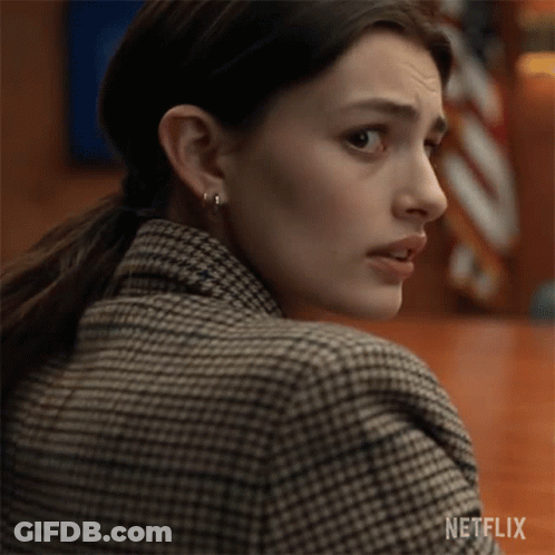 A Close Up Of A Woman Wearing A Plaid Jacket And Earrings . GIF