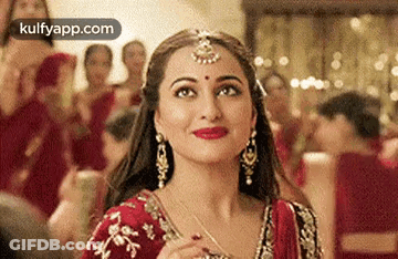 A Close Up Of A Woman Wearing A Red And Gold Dress And Earrings . GIF