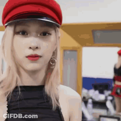 A Close Up Of A Woman Wearing A Red Hat And Earrings GIF
