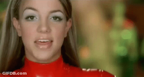 A Close Up Of A Woman Wearing A Red Latex Outfit And White Eye Shadow . GIF