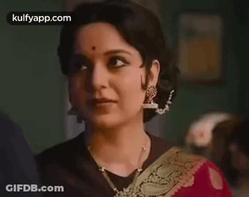 A Close Up Of A Woman Wearing A Red Saree And Gold Earrings . GIF