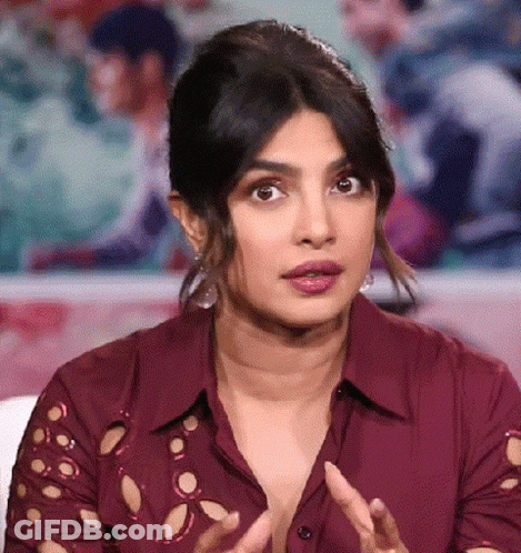 A Close Up Of A Woman Wearing A Red Shirt With Holes In The Sleeves Making A Funny Face . GIF