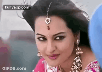 A Close Up Of A Woman Wearing A Saree And Earrings . GIF