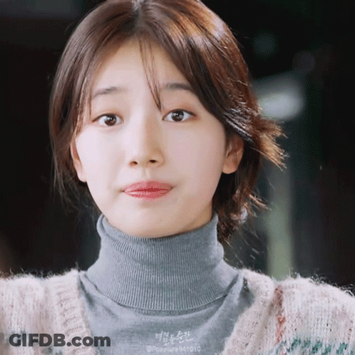 A Close Up Of A Woman Wearing A Turtleneck And A Sweater GIF