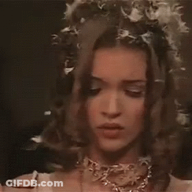 A Close Up Of A Woman Wearing A Veil And A Necklace With Flowers In Her Hair . GIF