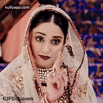 A Close Up Of A Woman Wearing A Veil And A Necklace . GIF