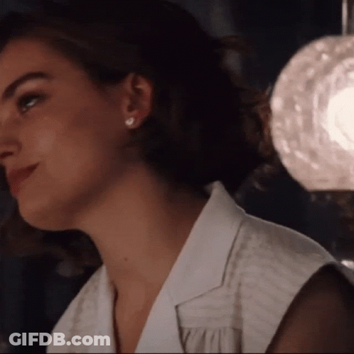 A Close Up Of A Woman Wearing A White Shirt And Earrings GIF