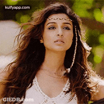 A Close Up Of A Woman Wearing A White Top And A Headband . GIF