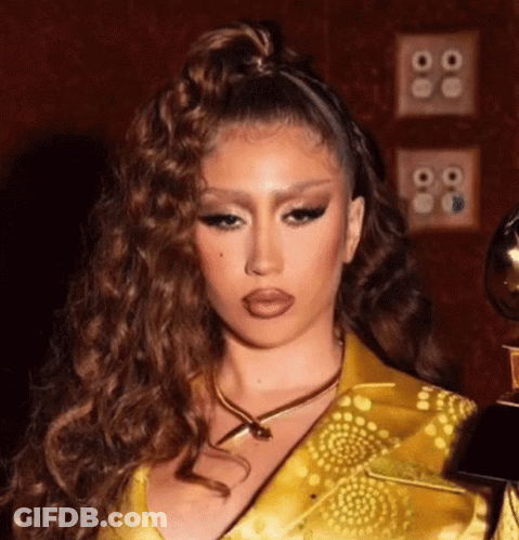 A Close Up Of A Woman Wearing A Yellow Dress And A Gold Necklace Holding A Trophy . GIF