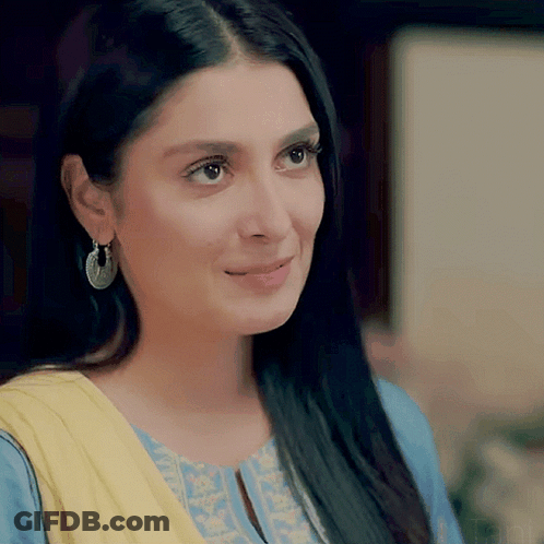 A Close Up Of A Woman Wearing Earrings And A Blue And Yellow Dress GIF