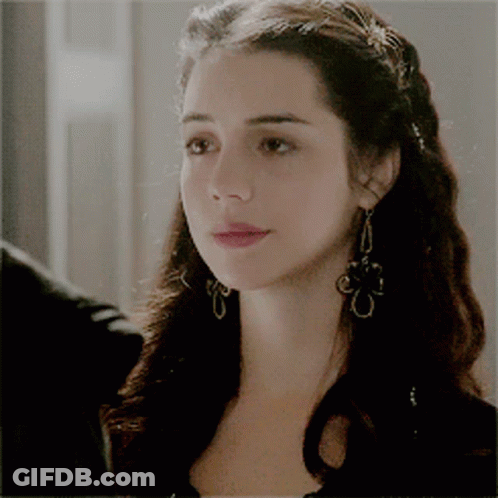 A Close Up Of A Woman Wearing Earrings And A Braided Hairstyle GIF