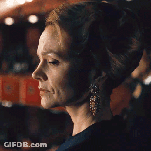 A Close Up Of A Woman Wearing Earrings And A Bun GIF