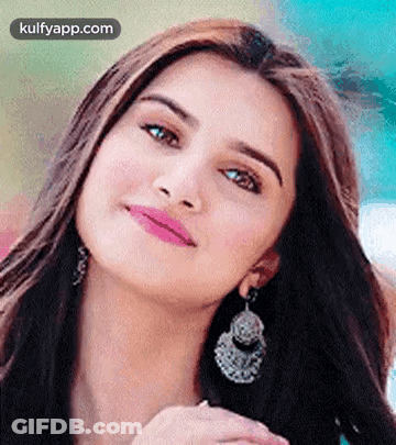 A Close Up Of A Woman Wearing Earrings And A Pink Lip Gloss . GIF