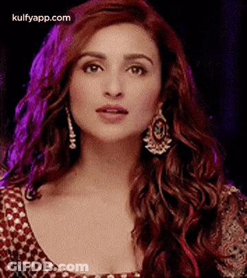 A Close Up Of A Woman Wearing Earrings And A Red Dress . GIF