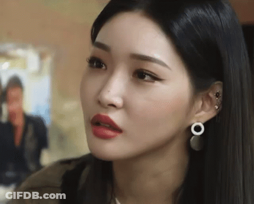 A Close Up Of A Woman Wearing Earrings And Red Lipstick Making A Funny Face . GIF