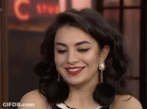 A Close Up Of A Woman Wearing Earrings And Red Lipstick Smiling . GIF