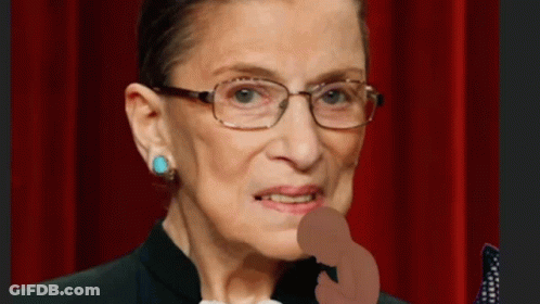A Close Up Of A Woman Wearing Glasses And A Black Suit GIF