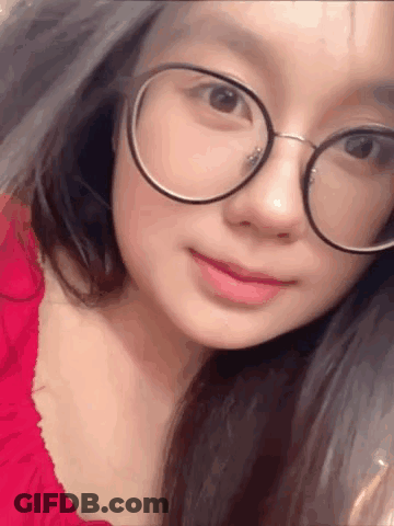 A Close Up Of A Woman Wearing Glasses And A Red Dress . GIF