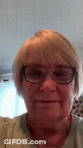 A Close Up Of A Woman Wearing Glasses And A Tan Shirt GIF