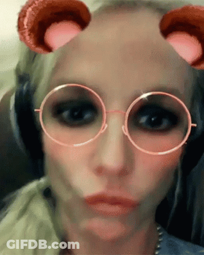 A Close Up Of A Woman Wearing Glasses And Headphones Making A Face GIF