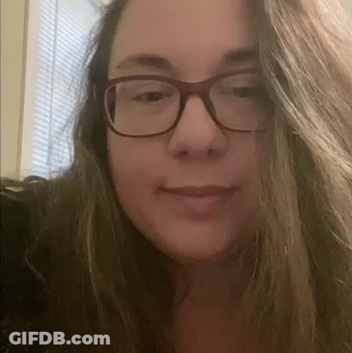 A Close Up Of A Woman Wearing Glasses And Smiling At The Camera . GIF