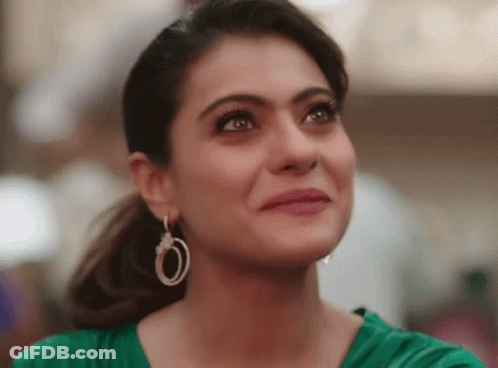 A Close Up Of A Woman Wearing Hoop Earrings And A Green Top GIF