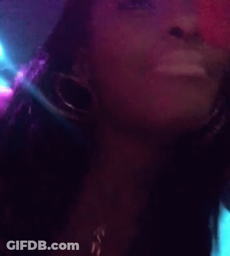 A Close Up Of A Woman Wearing Hoop Earrings And A Necklace With The Letter C On It GIF