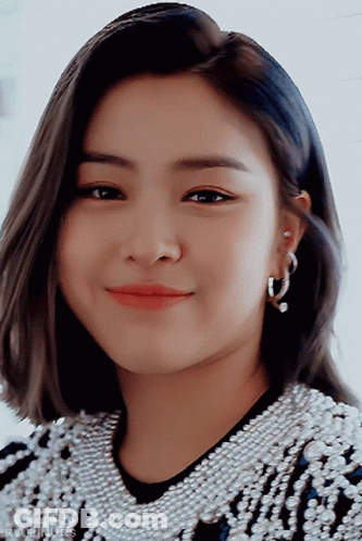 A Close Up Of A Woman Wearing Hoop Earrings And A Sweater With Pearls GIF