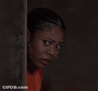 A Close Up Of A Woman Wearing Hoop Earrings And An Orange Shirt GIF