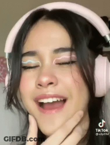 A Close Up Of A Woman Wearing Pink Headphones . GIF
