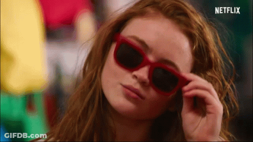 A Close Up Of A Woman Wearing Red Sunglasses With A Netflix Logo In The Corner GIF